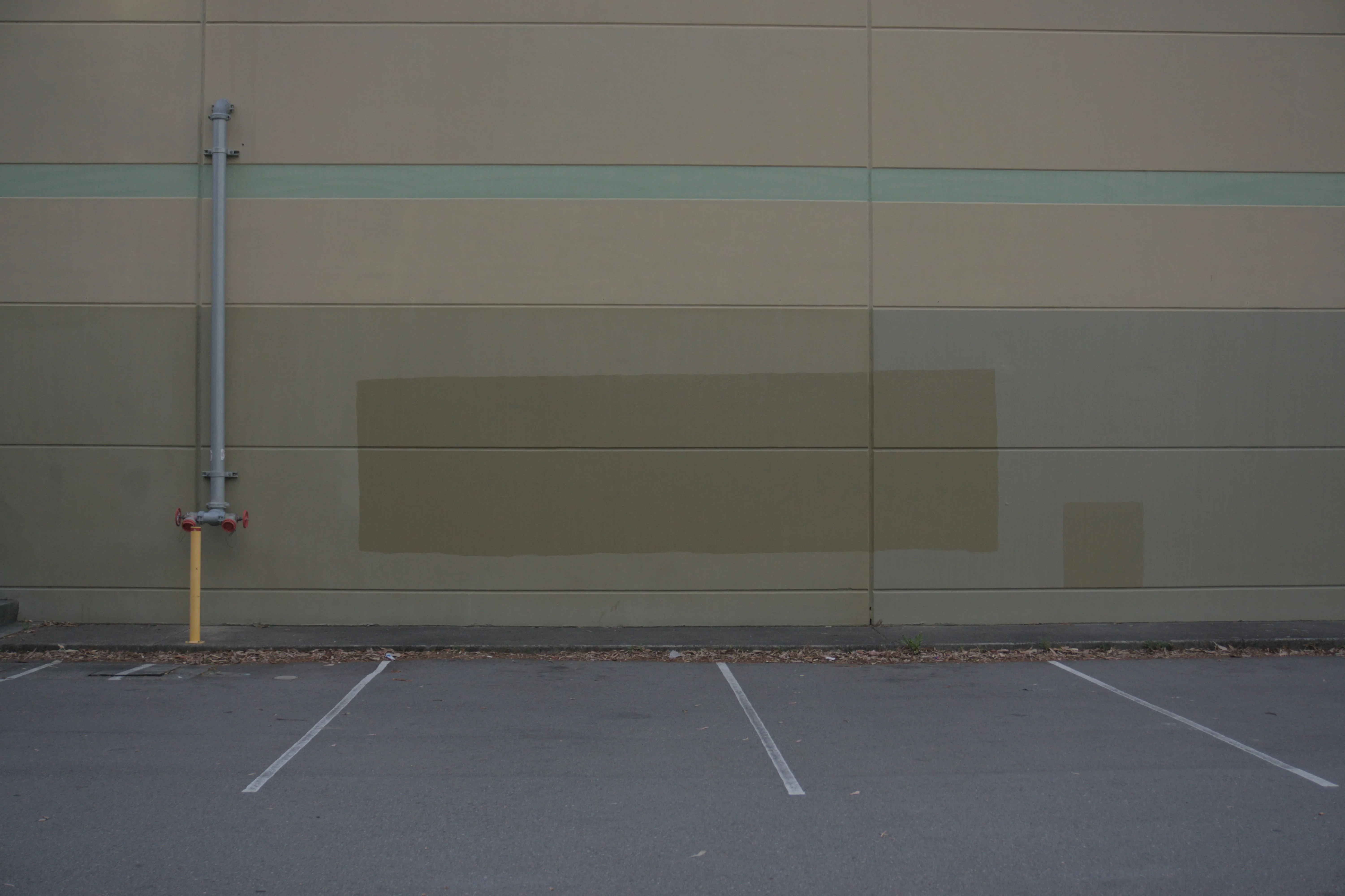 A wall in front of parking spaces that has had graffiti covered over with new paint