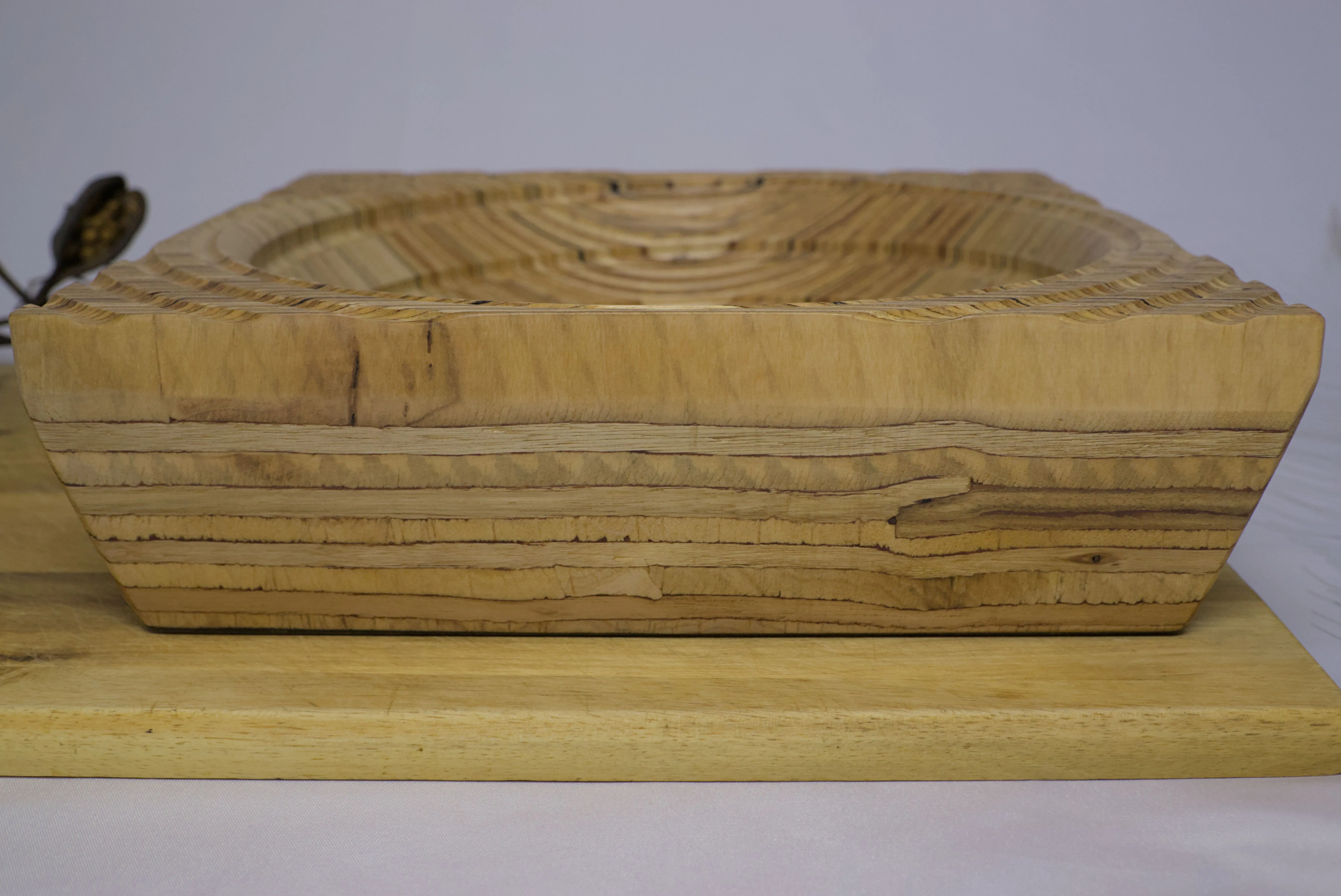 Side view of a plywood bowl with a groove spiralling towards the center.